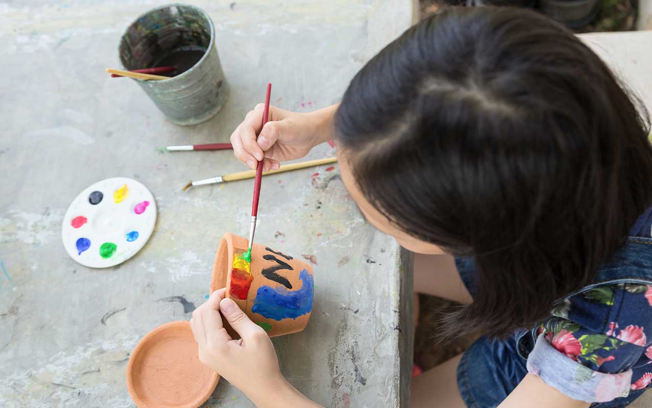 Young girl painting on pottery